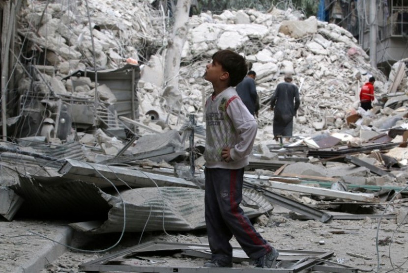 Seorang anak menyaksikan bangunan bekas pengeboman di Aleppo, Suriah.