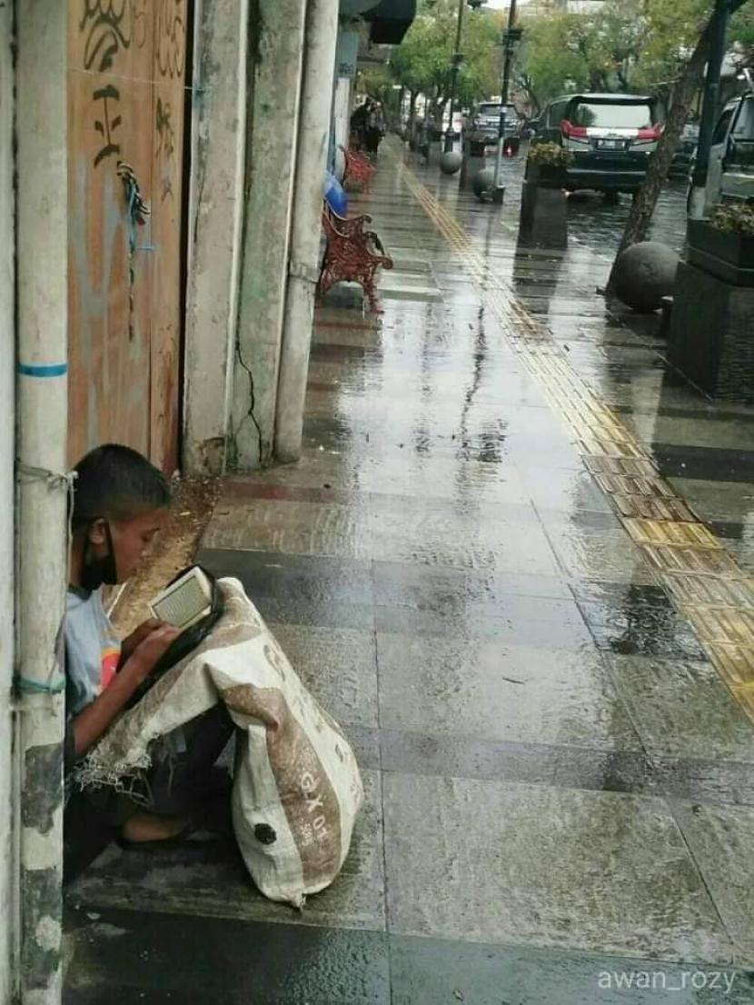 Seorang anak pemulung sedang membaca Alquran saat berteduh dari hujan di Jalan Braga, Kota Bandung mendadak viral di media sosial.