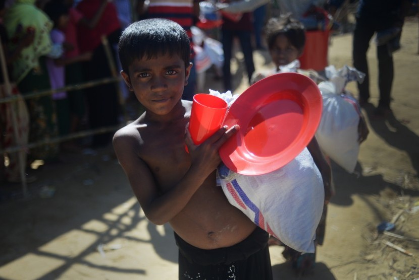 Seorang anak pengungsi Rohingya membawa barang bantuan yang baru diterimanya di Kamp Pengungsian Jamtoli, Cox Bazar, Bangladesh. 