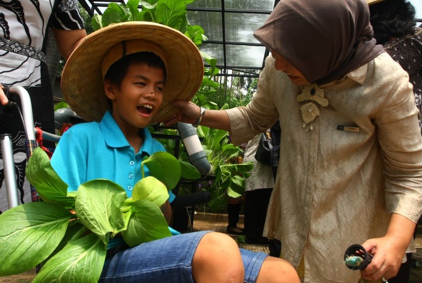 Seorang anak penyandang disabilitas menunjukan sayuran yang baru dipanennya hasil dari tanamannya sebulan yang lalu di Yayasan Sayap Ibu, Bintaro, Tangerang Selatan, Banten, Senin (14/3).