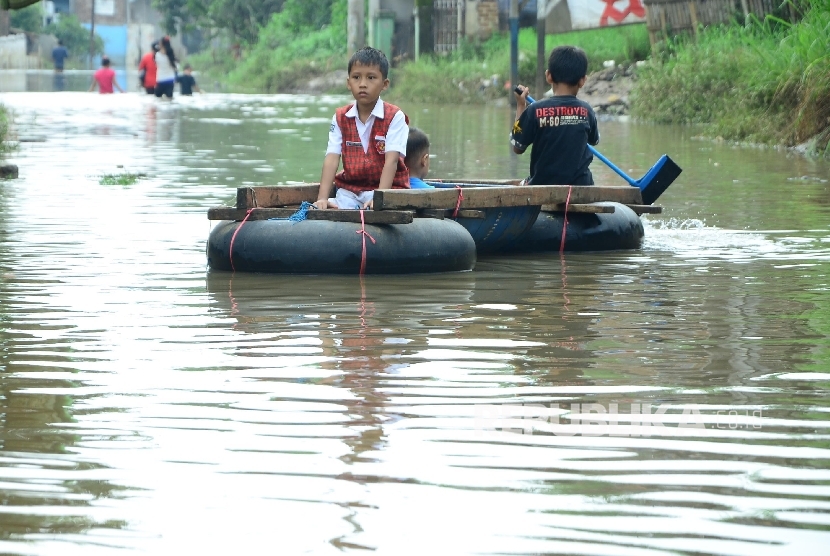 Seorang anak pulang sekolah di bonceng temannya menggunakan rakit di Jl Cibadak, Kecamatan Dayeuhkolot, Kabupaten Bandung, Senin (31/10).