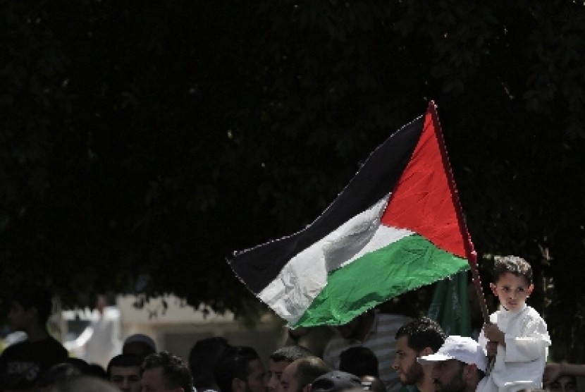 Seorang anak tengah memegang bendera Palestina di Gaza. Hingga saat ini, pembicaraan damai Israel-Palestina berjalan alot, Hamas selaku otoritas di Gaza menginginkan Israel mencabut blokade. Sebaliknya, Israel menolak usulan tersebut. 