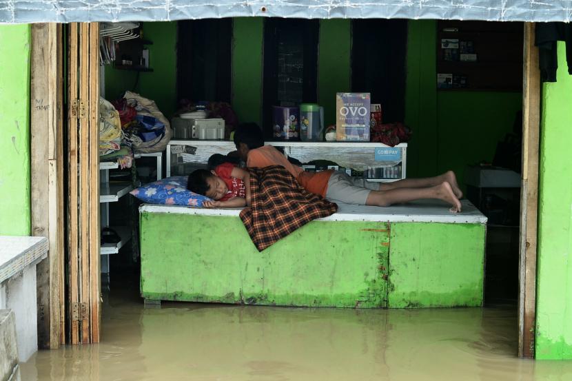 Seorang anak tertidur dirumahnya yang terendam banjir di Lemah Abang, Cikarang Utara, Bekasi, Jawa Barat, Sabtu (20/2/2021). Menurut keterangan warga, hujan deras yang mengguyur wilayah Kabupaten Bekasi sejak Kamis (18/2/2021) malam hingga Jumat (19/2/2021) pagi mengakibatkan meluapnya Kali Cilemah Abang hingga merendam sejumlah jalan dan pemukiman warga.