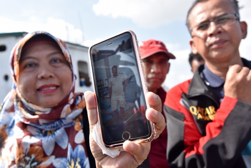 Seorang anggota keluarga penumpang Kapal Zahro Express yang terbakar memperlihatkan foto salah satu korban hilang di Pelabuhan Kali Adem, Muara Angke, Jakarta, Senin (2/1). 