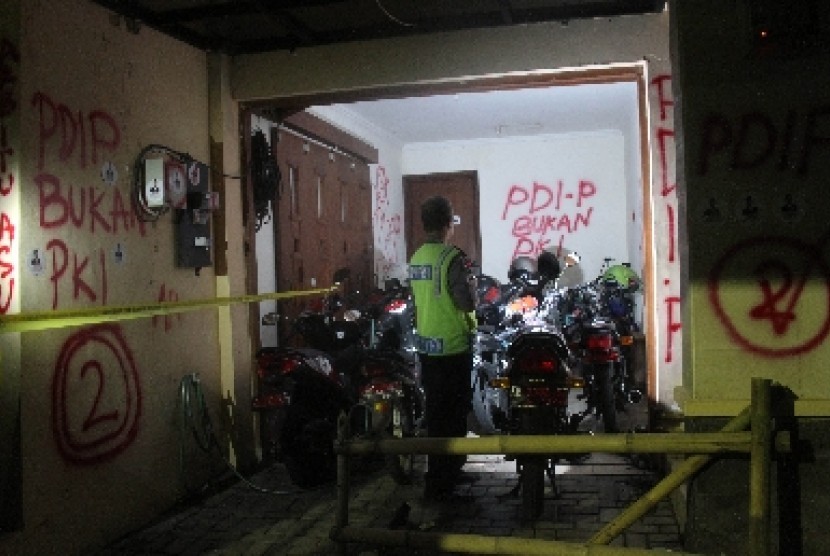 Seorang anggota kepolisian mengecek kerusakan yang terjadi di kantor Tv One Biro Yogyakarta, Rabu (2/7) malam. 