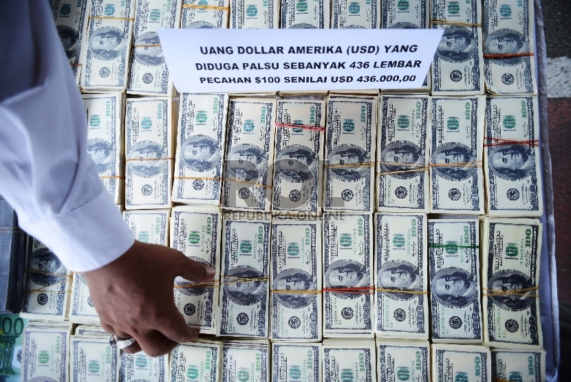 Seorang anggota kepolisian menunjukan uang dolar palsu. (Republika/Raisan Al Farisi)