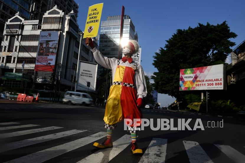 Seorang anggota komunitas Aku Badut Indonesia (ABI) melakukan aksi dengan mambawa poster di kawasan Fatmawati Jakarta, Senin (12/7/2021). Aksi tersebut untuk mengajak masyarakat menerapkan protokol kesehatan untuk mencegah penyebaran COVID-19 yang terus meningkat. 