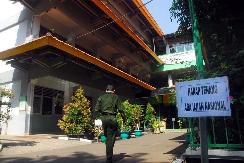 Seorang anggota panitia Ujian Nasional melintas didepan Sekolah Menengah Kejuruan (SMK) Negeri 8 Jakarta saat ujian nasional berlangsung, Senin (16/4). 