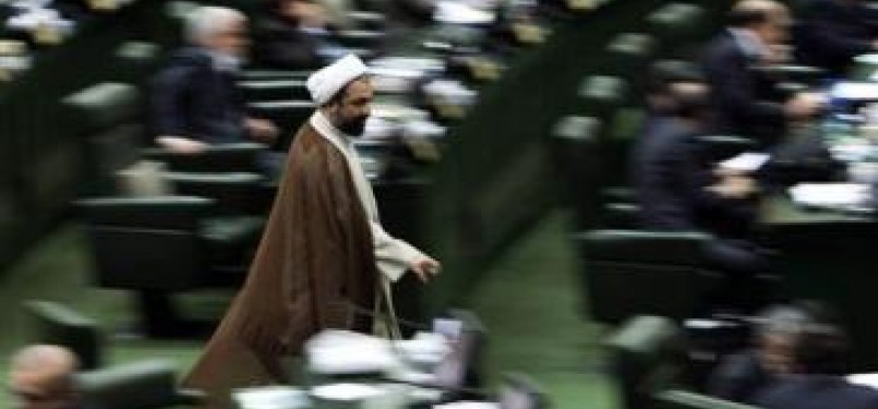Seorang anggota parlemen berjalan di ruang sidang parlemen Iran 