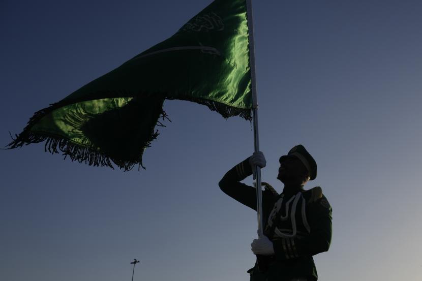 Seorang anggota pasukan khusus Arab Saudi mengangkat bendera nasional Saudi.