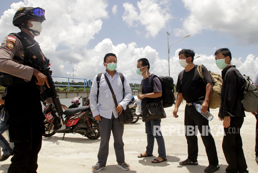 Seorang anggota polisi mengawal sejumlah warga negara China yang terdampar di perairan Rote Ndao setibanya di Lantamal VII Kupang, NTT, Kamis (30/1/2020).