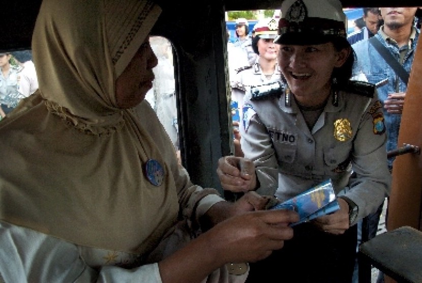 Seorang anggota Polwan menyematkan pin pada seorang penumpang angkot ketika memperingati Hari Anti Kekerasan Terhadap Perempuan dan Anak di Monumen Perjuangan Polri Surabaya, Jatim, Senin (26/11).