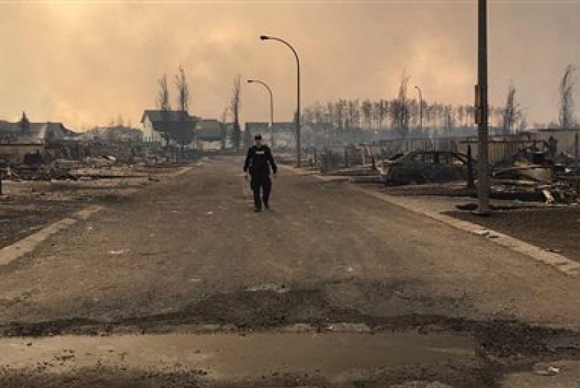 Seorang anggota Royal Canadian Mounted Police Alberta memeriksa kehancuran yang disebabkan kebakaran besar di Fort McMurray, Alberta, Kanada, 5 Mei 2016. 