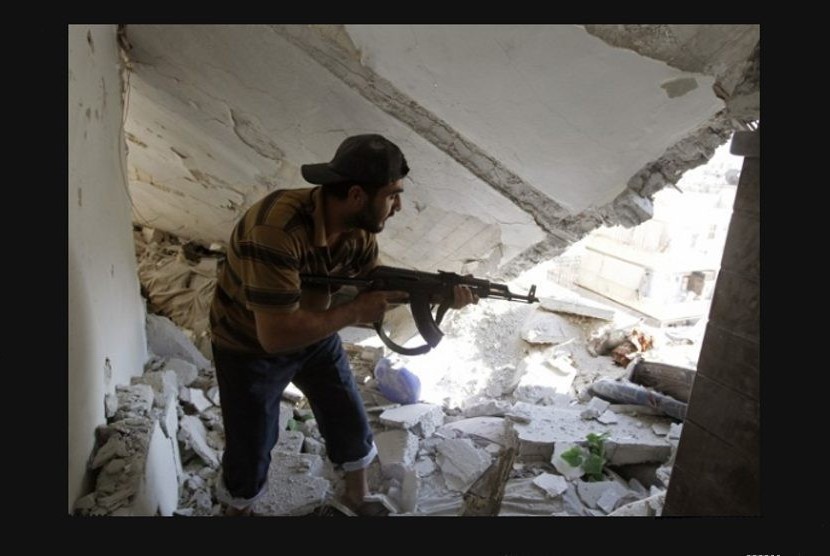 Seorang anggota Tentara Pembebasan Suriah berjalan di puing reruntuhan apartemen yang diserang peluru tank militer ketika bentrok terjadi di Aleppo (/Reuters/Goran Tomasevic)
