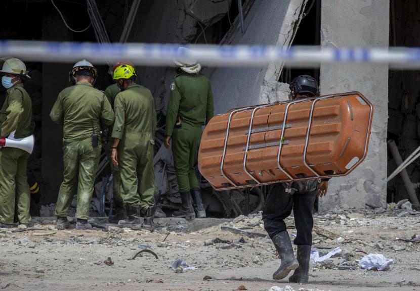 Seorang anggota tim penyelamat membawa tandu untuk mengangkut mayat orang yang ditemukan di puing-puing setelah ledakan mematikan yang menghancurkan Hotel Saratoga bintang lima di Old Havana, Kuba, Ahad, 8 Mei 2022.
