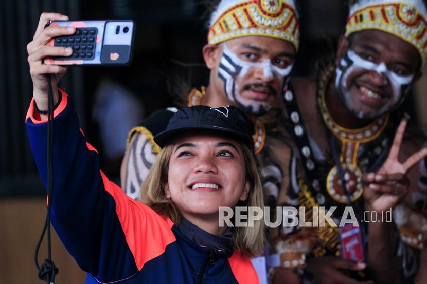 Seorang atlet DKI Jakarta berfoto dengan penari yang menyambut kontingan DKI Jakarta di Bandara Sentani, Jayapura, Papua, Senin (20/9/2021). PON Papua berlangsung pada 2 - 15 Oktober 2021. 