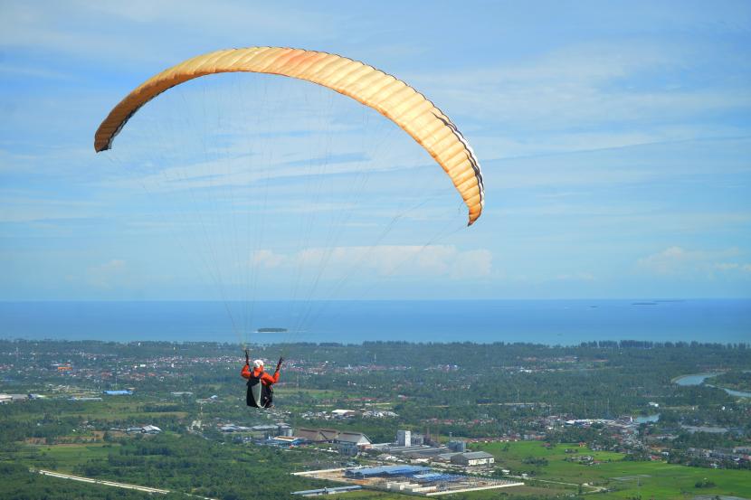 Seorang atlet paralayang terbang dengan latar Samudera Hindia, dari Gunung Kanter, Nagari Sungai Buluh Selatan, Kabupaten Padangpariaman, Sumatera Barat.