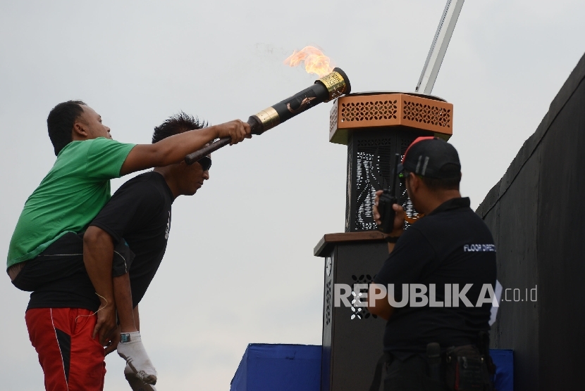 Seorang atlet Pekan Paralimpik Nasional (Peparnas) menyalakan obor api Peparnas saat mengikuti gladi resik di Stadion Siliwangi, Bandung, Jawa Barat, Jumat (14/10). 