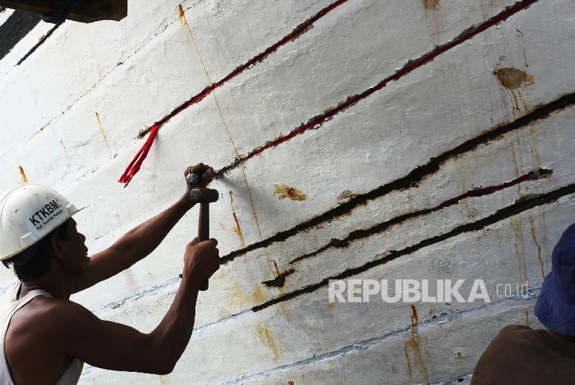 Seorang awak kapal tradisional nampak memperbaiki lambung kapal yang sudah kurang baik yaitu dengan menambalnya di Pelabuhan Sunda Kelapa, Jakarta, Rabu (18/1).