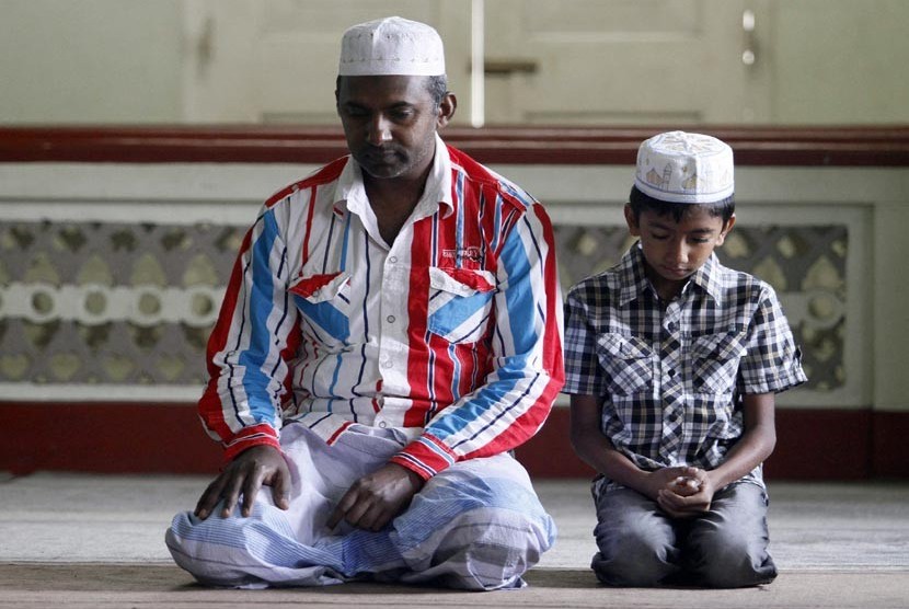   Seorang ayah bersama anaknya tengah menanti pelaksanaan shalat Idul Fitri di Kandy, Srilanka, Ahad (19/8).  (Dinuka Liyanawatte/Reuters)