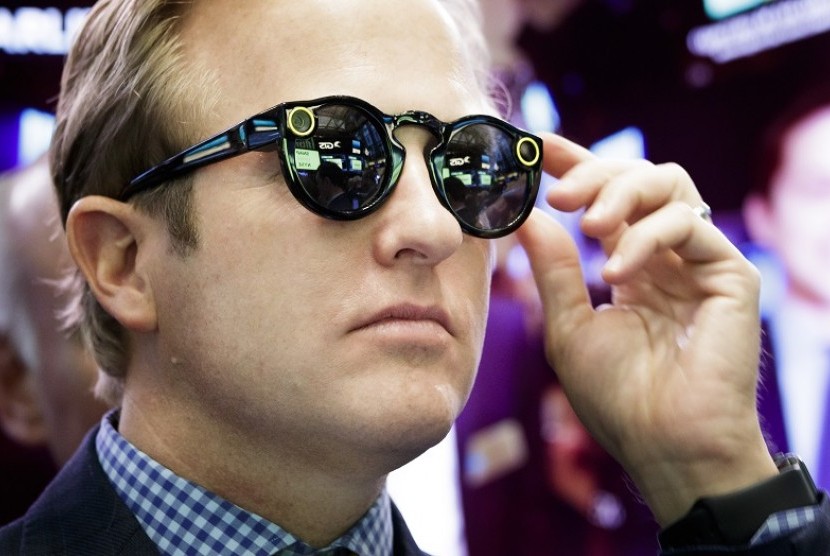 Seorang bankir yang mengenakan Snapchat Spectacles menyaksikan penawaran umum perdana Snap Inc, perusahaan induk Snapchat