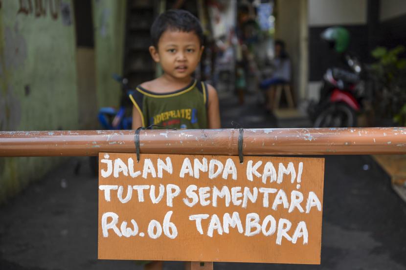 Seorang bocah berdiri di belakang portal karantina wilayah di kawasan Tambora, Jakarta, Jumat (3/4/2020). Warga setempat memberlakukan karantina wilayah secara mandiri dengan menutup beberapa akses jalan masuk perkampungan serta meningkatkan keamanan untuk mencegah penyebaran COVID-19.