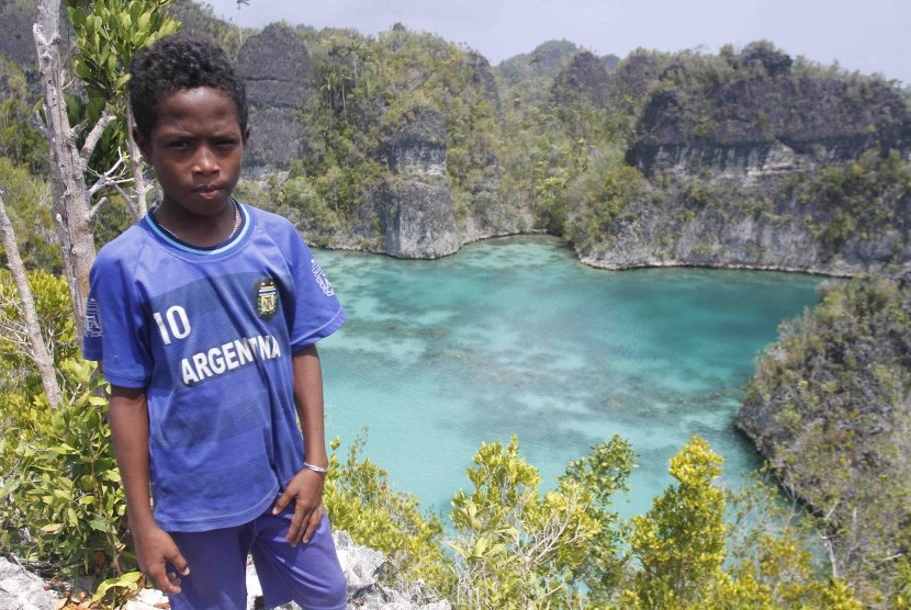 Seorang bocah berpose dengan latar belakang telaga bintang di Raja Ampat, Papua Barat, Senin (2/11). Raja Ampat merupakan destinasi wisata di Papua Barat yang mendunia.