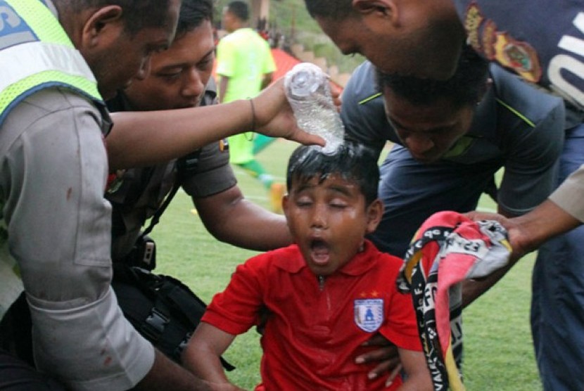 Seorang bocah diberi air setelah terkena gas air mata yang dilepaskan oleh Polisi saat terjadi kerusuhan pada pertandingan sepakbola antara Persipura melawan Persija di stadion Mandala Jayapura, Papua, Minggu (13/05). Kerusuhan di picu aksi pemukulan pemai