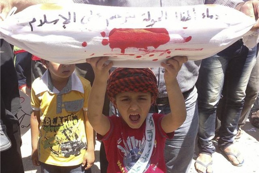 Seorang bocah lelaki memegang sarung guling replika jasad mati saat menggela demonstrasi menentang Presiden Suriah, Bashar al-Assad di Binsh, Idlib, pada Sabtu (2/6) 