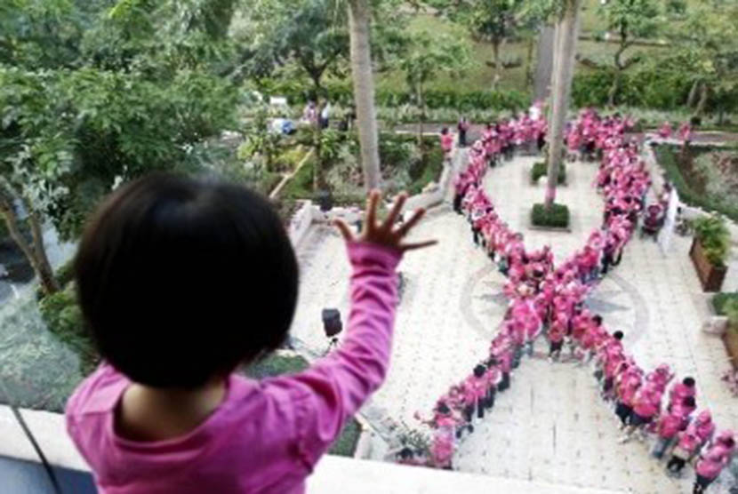 Seorang bocah melihat formasi pita dari manusia saat Kampanye Kesadaran akan Kanker Payudara di Jakarta. 