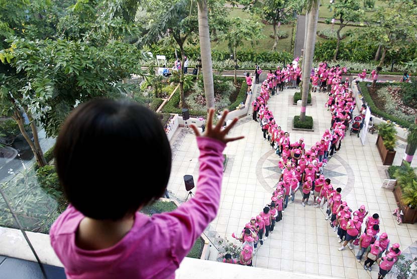 Seorang bocah melihat formasi pita dari manusia saat Kampanye Kesadaran akan Kanker Payudara di Jakarta. 