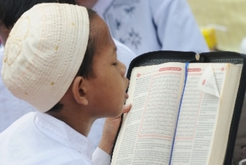 Seorang bocah membaca Alquran dalam kegiatan khataman Alquran secara massal.