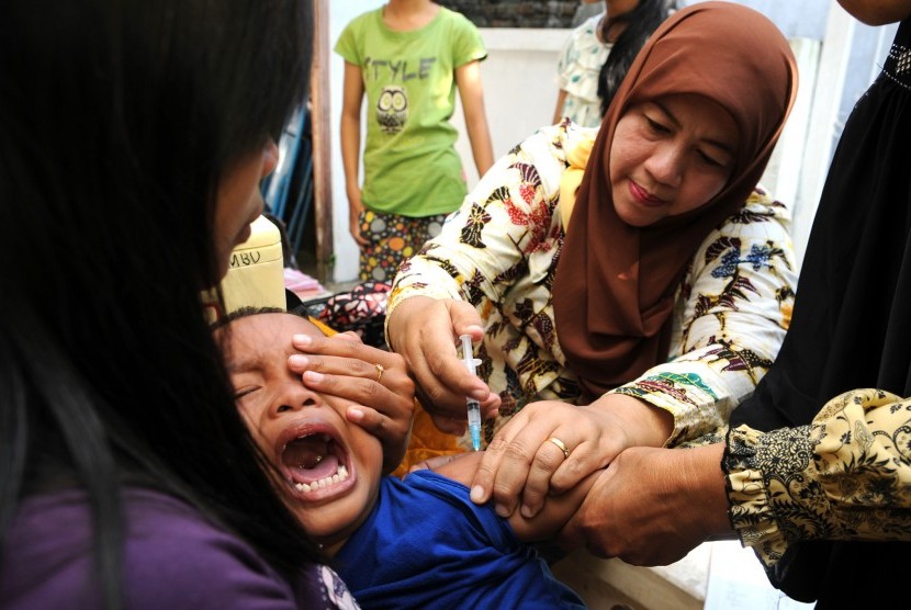 Seorang bocah mendapatkan vaksin DPT (Difteri, Pertusis dan Tetanus) tambahan saat vaksin difteri massal berbagai usia di Desa Plandi, Jombang, Jawa Timur.