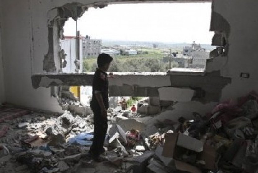 Seorang bocah Palestina memeriksa rumah keluarganya yang hancur akibat serangan udara Israel di timur kota Gaza, Jumat (8/4).