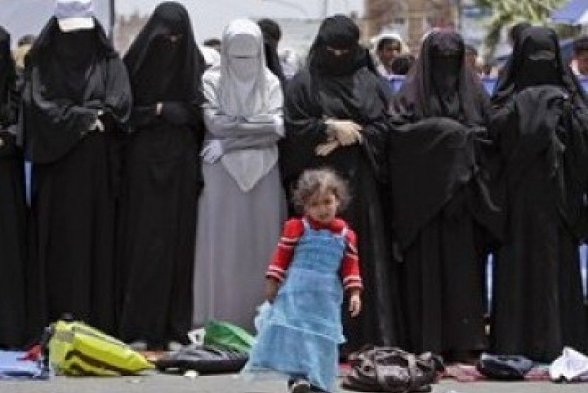 Seorang bocah perempuan berdiri di depan kaum wanita Yaman yang shalat di sela-sela demonstrasi menentang Presiden Saleh.