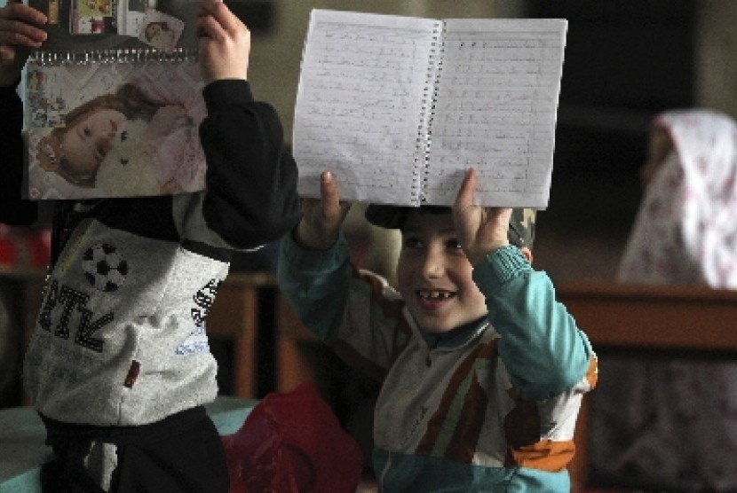 Seorang bocah tersenyum saat memerlihatkan buku ketika mengikuti kelas yang digelar aktivis di sebuah masjid di Aleppo, Suriah