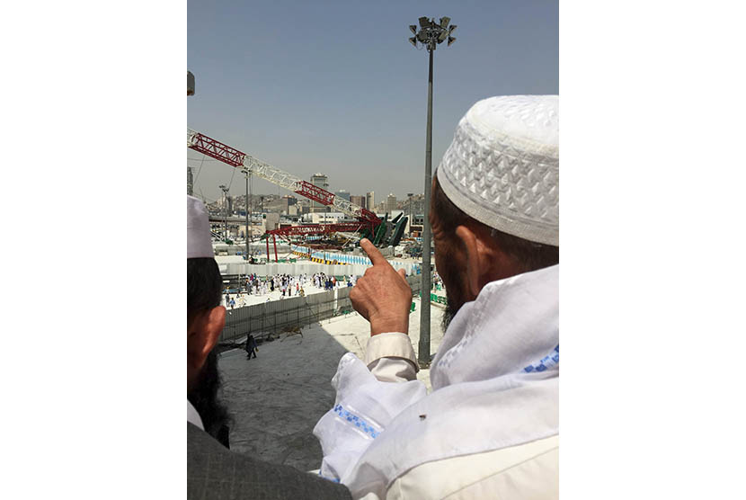 Seorang calon jamaah haji menunjuk ke arah crane proyek perluasan masjid yang jatuh di Masjidil Haram, Makkah, Sabtu (12/9).   (Reuters/Mohamed Al Hwaity)