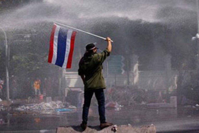 Seorang demonstran anti-pemerintahan Thailand mengibarkan bendera di tengah semprotan water canon pasukan antihuru-hara pemerintah.