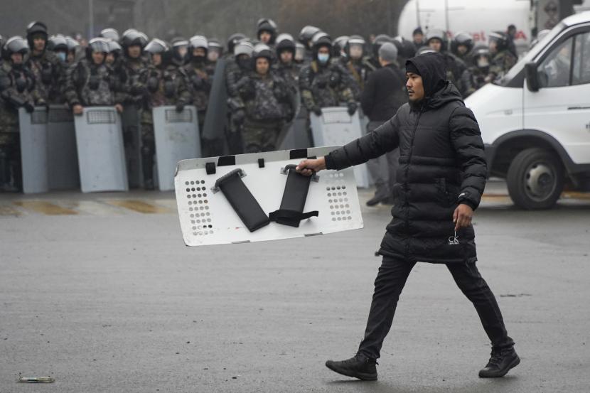 Seorang demonstran membawa perisai polisi di depan garis polisi selama protes di Almaty, Kazakhstan, Rabu, 5 Januari 2022.