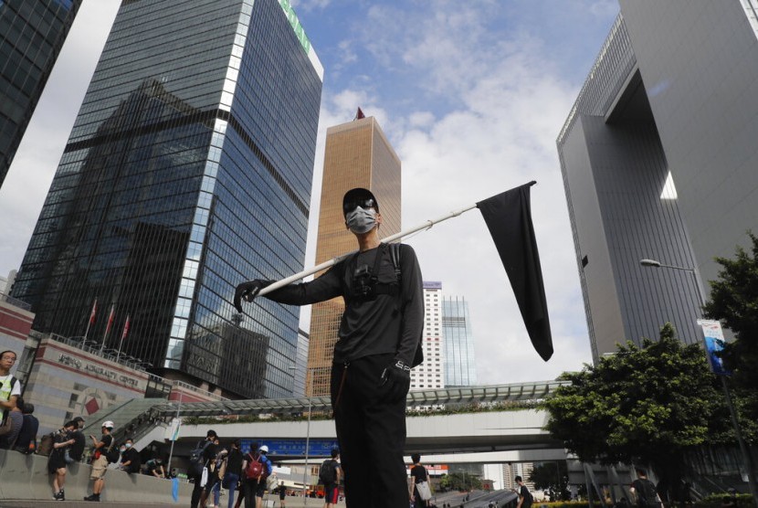 Seorang demonstran memegang bendera hitam sebagai simbol dukacita bagi Hong Kong dalam protes di Hong Kong, Senin (1/7).