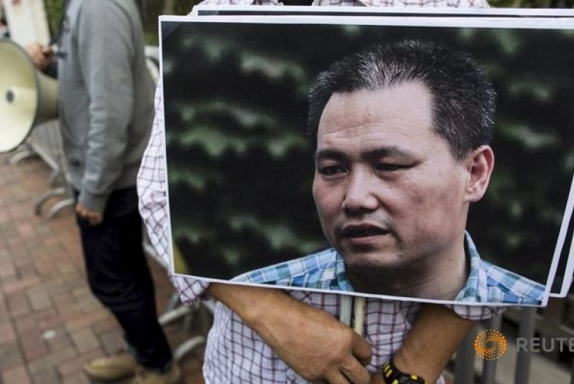 Seorang demonstran memegang foto pengacara hak asasi manusia terkemuka Cina Pu Zhiqiang, menuntut pembebasannya.