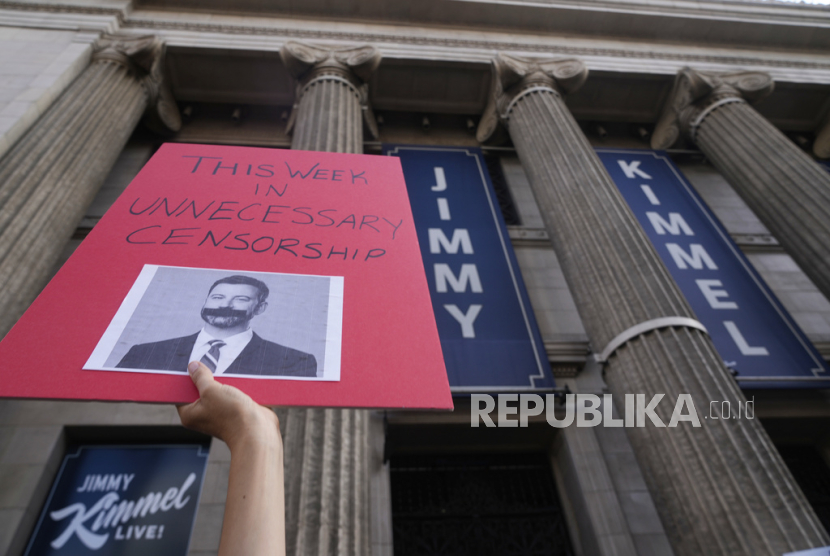 Seorang demonstran memegang spanduk di luar El Capitan Entertainment Centre, tempat pertunjukan larut malam Jimmy Kimmel Live! digelar pada Kamis (18/9/2025) di Los Angeles, AS.