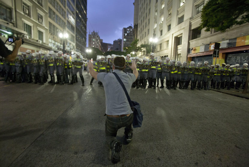 Seorang demonstran menantang pasukan polisi dalam aksi protes anti-Piala Dunia 2014 di Sao Paulo, Brasil, akhir Februari lalu.