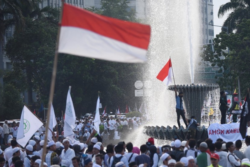 Seorang demonstran mengibarkan bendera dalam aksi dalam aksi 4 November di Jakarta, Jumat (4/11). 