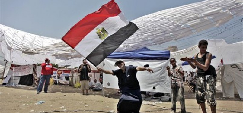 Seorang demonstran Mesir menari seraya melambaikan bendera negaranya dalam unjuk rasa di Tahrir Square, Kairo.