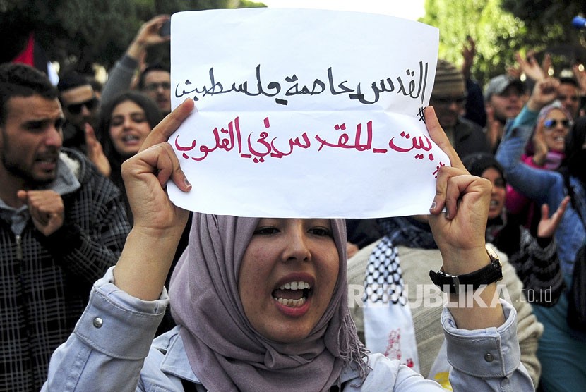 Seorang demonstran Tunisia memegang sebuah poster bertuliskan ibukota Yerusalem Palestina. Yerusalem, Kamis (7/12).