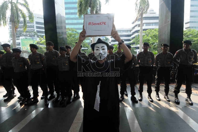   Seorang demostran mengenakan topeng yang teragabung dalam Front Perjuangan Rakyat (FPR) melakukan aksi didepan Gedung KPK, Jakarta, Rabu (28/1). (Republika/Agung Supriyanto)