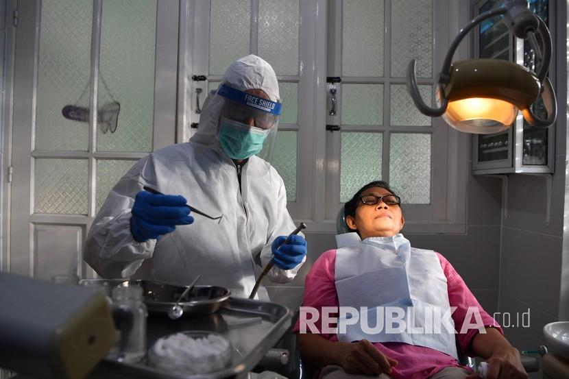 Seorang dokter gigi mengenakan alat pelindung diri (APD) saat memeriksa pasiennya di salah satu klinik di Surabaya, Jawa Timur, Jumat (15/5/2020). Penggunaan APD tersebut untuk mengantisipasi penyebaran COVID-19 dan menjadi Standar Operasional Prosedur (SOP) pemeriksaan gigi saat pandemi. 