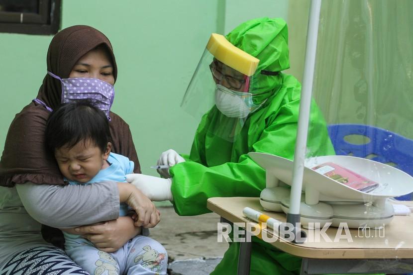 Seorang dokter mengenakan Alat Pelindung Diri (APD) saat melakukan imunisasi kepada anak di Puskesmas Cisalak Pasar, Depok, Jawa Barat