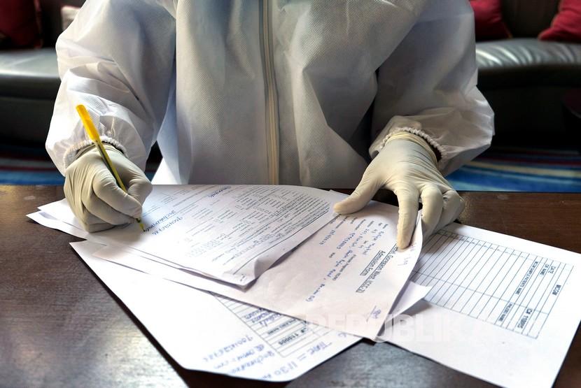 Seorang dokter mengisi formulir untuk tes swab kedua dari fotografer Associated Press Rafiq Maqbool di kamar hotel tempat ia di karantina di Mumbai, India, Jumat (24/4). Maqbool merupakan salah satu dari jurnalis yang dinyatakan positif COVID-19 dan pindah secara kolektif ke hotel yang diubah menjadi pusat karantina. Dia meninggalkan istri dan anak-anaknya di rumahdengan kondisi yang tertutup untuk menjauhkan rasa cemas dan stigma negatif kepada kerabat. Pada hari ketujuh, hasil dari tes swab kedua memberikan hasil negatif dan dia diizinkan kembali ke rumah untuk dikarantina selama 14 hari. 